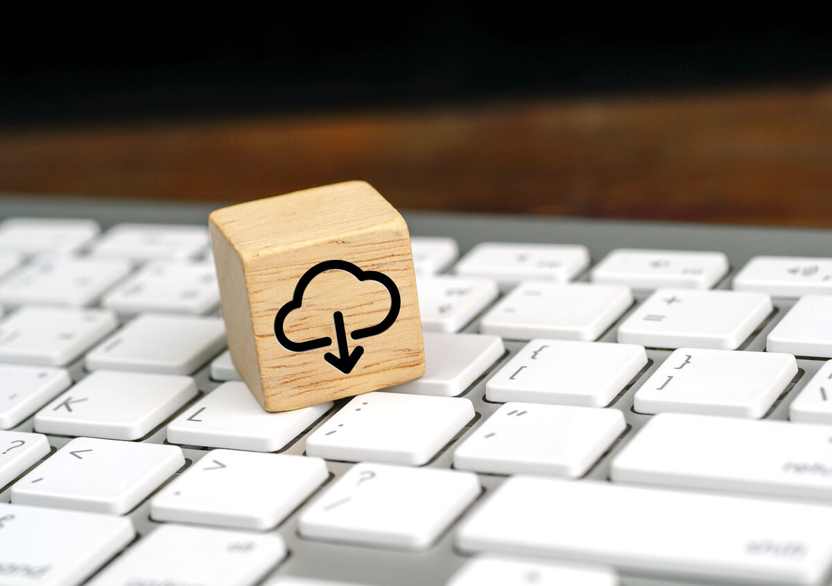 Holzw&uuml;rfel mit Cloud-Download-Symbol auf einer Computertastatur.
