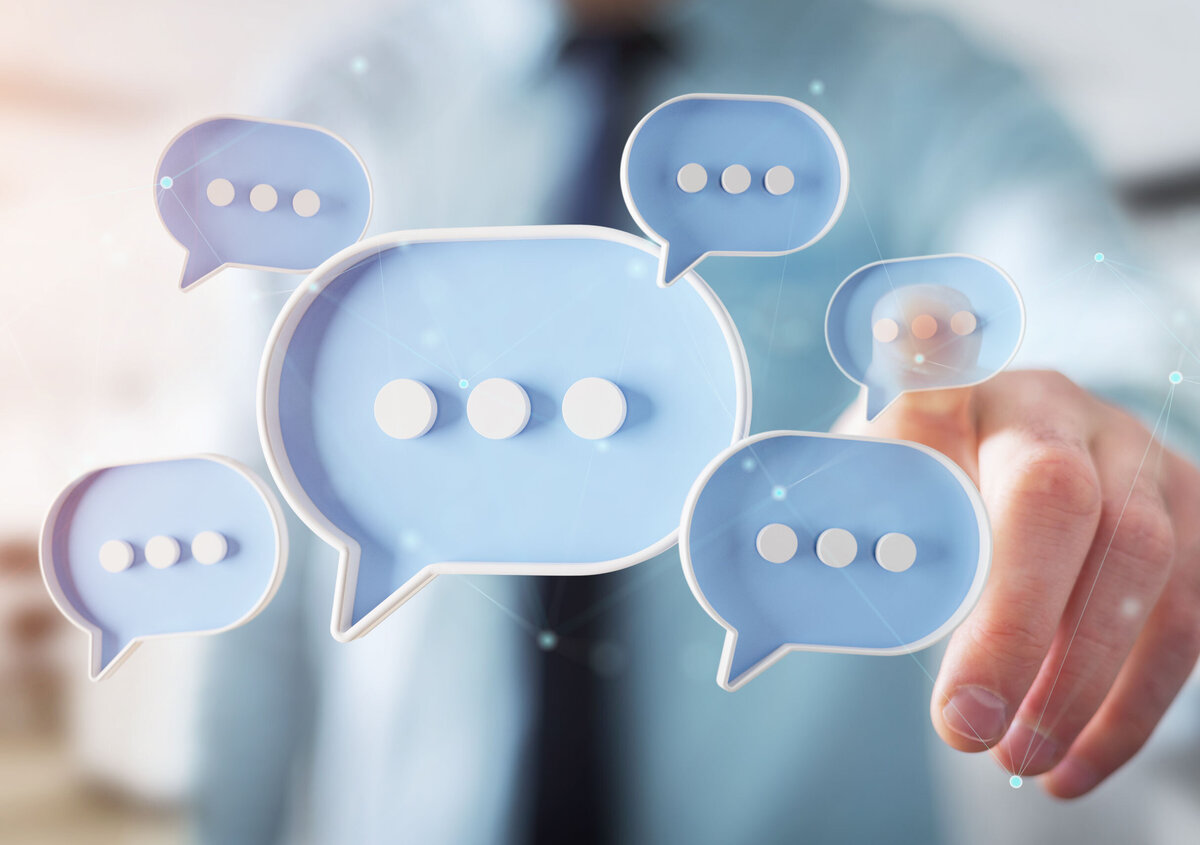 Digital speech bubbles in front of a person pointing at a virtual chat interface, symbolizing communication, messaging, and collaboration.