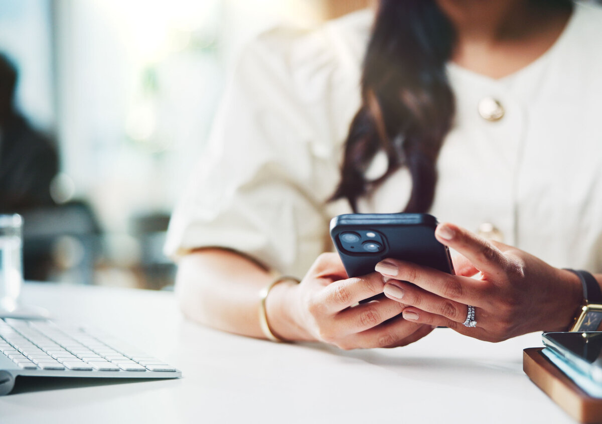Person verwendet ein Smartphone am Arbeitsplatz - Symbolbild f&uuml;r digitale Terminvereinbarungen und Online-Services.