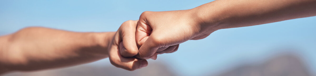 Two people bumping fists, symbolizing successful collaboration, implementation, and project delivery.