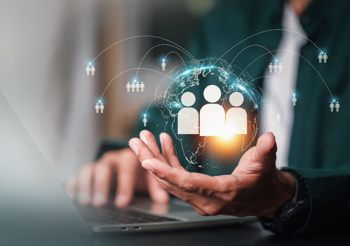 Person working on a laptop while holding a digital globe with connected people icons, symbolizing digital recruitment, HR services, talent management, and global workforce connectivity.