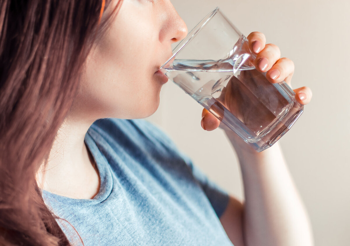 Close-up of a person drinking a glass of water. The image symbolizes clean drinking water, water quality, and sustainable water management.
