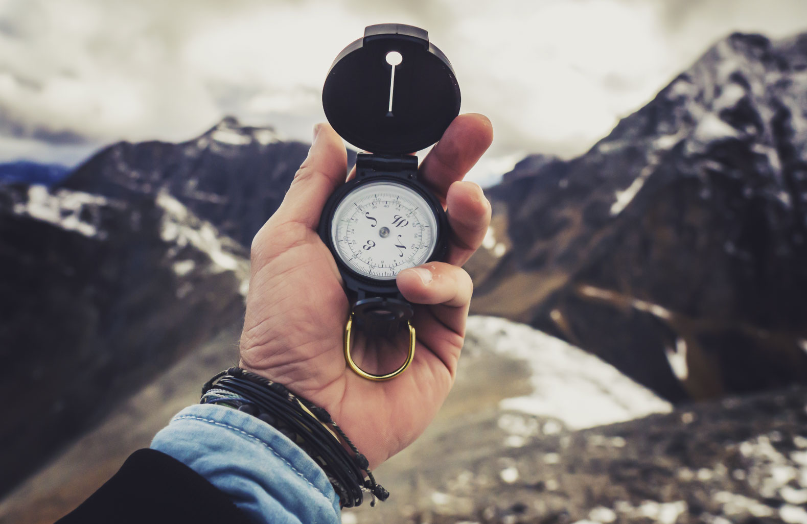 Aufnahme einer Hand mit Kompass im Hintergrund Berge