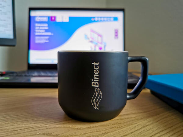 Aufnahme Schreibtisch mit Binect-Tasse und SmartDocuments-Notebook im Hintergrund